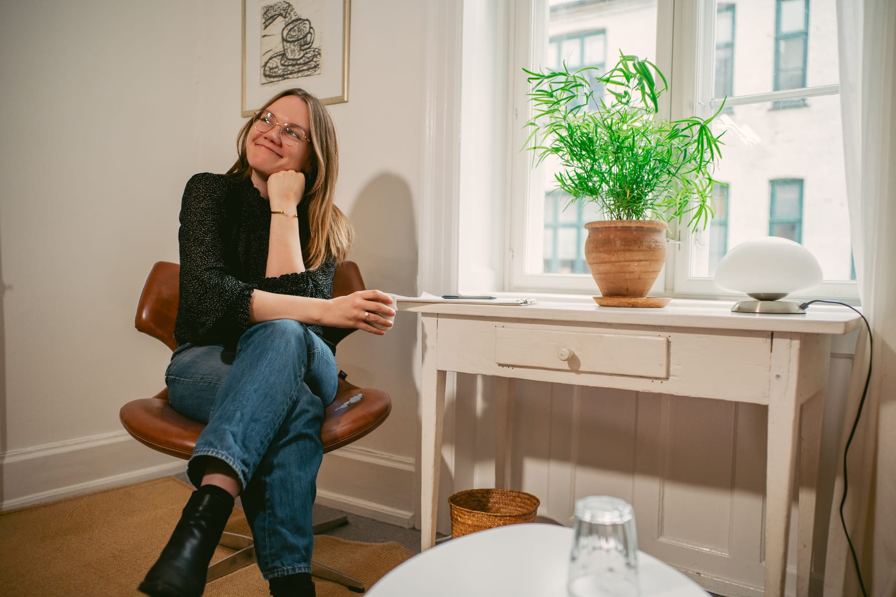 Psykolog Anna Langfred sidder i en stol ved vinduet og smiler