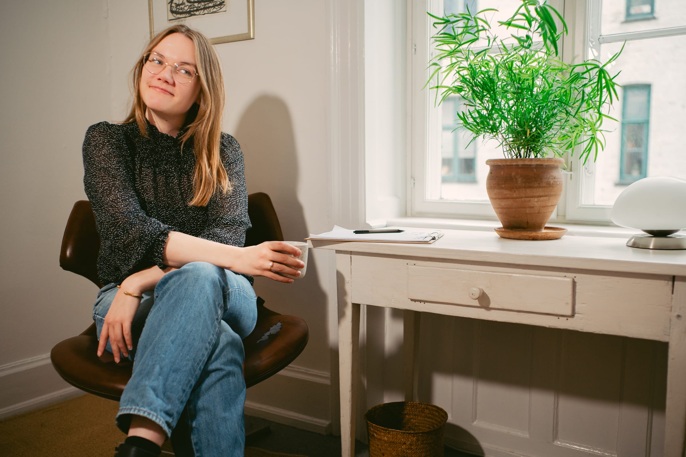 Psykolog Anna Langfred i terapirummet på Kroghsgade, ved vinduet med en grøn plante