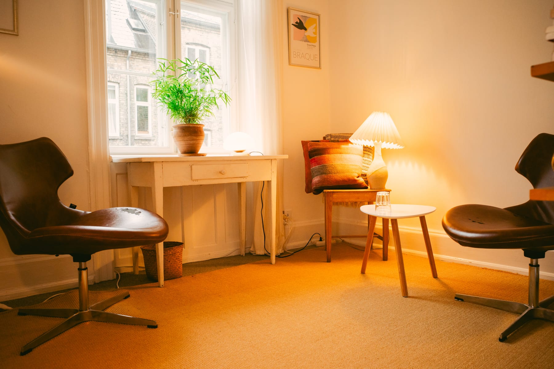 Terapirummet i klinikken med lædstole, et lille bord og en varm lampe